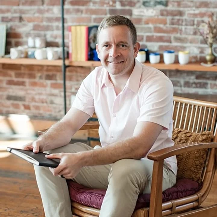 Mike Hoffmann seated in a rattan chair, holding a tablet.